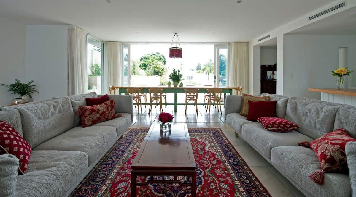 Combined living and dining room with facing sectionals, a wooden coffee table, and an elongated dining set that seats ten.