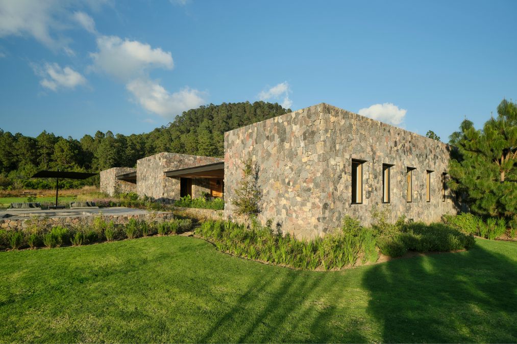 Set atop a verdant field, the FS House is constructed using rocks.