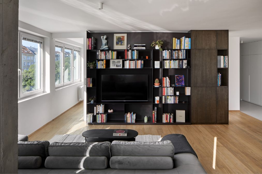 This is a close-up shot of the living section, with a focus on the full-height, black wall-mounted shelves.