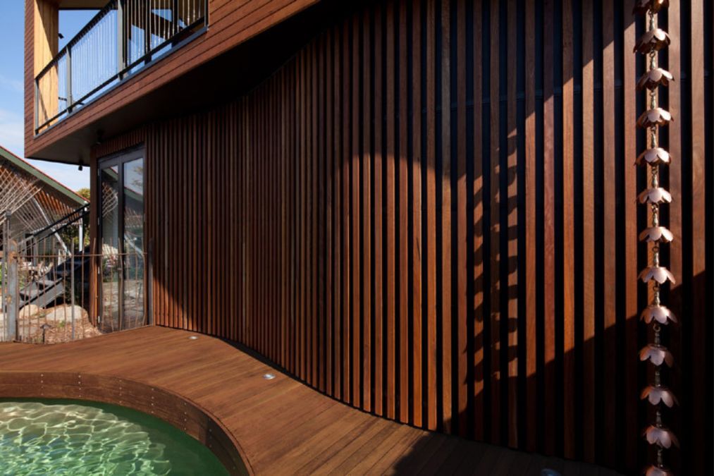 A close-up shot of the exterior wall made of timber which blends in water and rocks of the landscape.