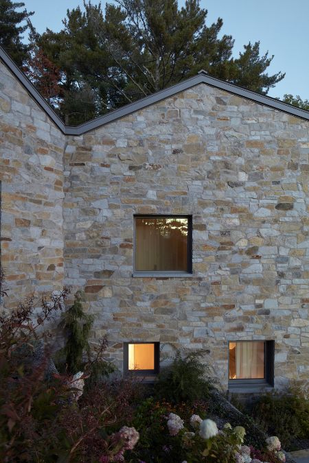 The exterior view reveals a stone edifice featuring an assortment of glass windows that vary in size.