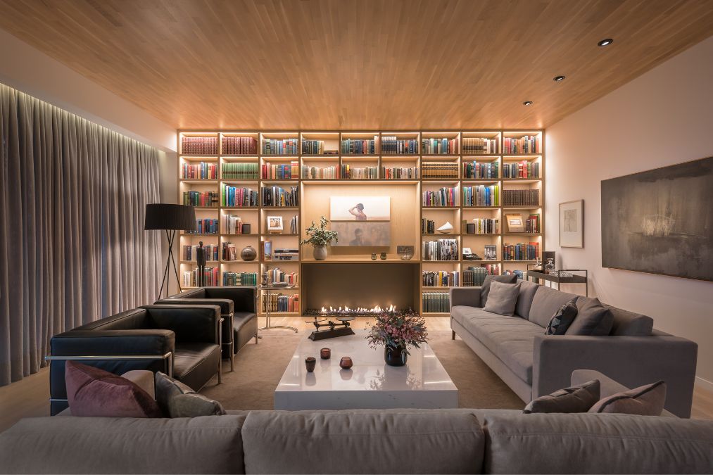 The living room is furnished and features a fireplace, while the walls are adorned with massive bookshelves. This creates an elegant and comfortable ambiance, suitable for relaxation and intellectual pursuits alike.