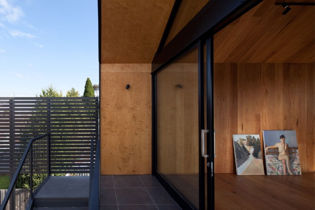 An image captured from the balcony of the house, featuring the sliding glass door which offers a glimpse of the interior design of the upper floor's room.