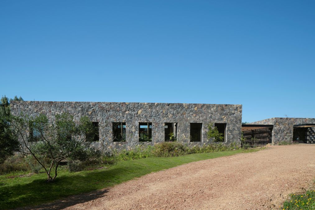 The FS House, a stone structure, is situated alongside a dirt road.