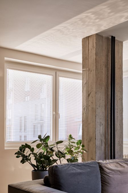 This is a detailed shot of the living section, highlighting the massive wooden planks column and the presence of indoor plants, creating a warm and inviting ambiance.