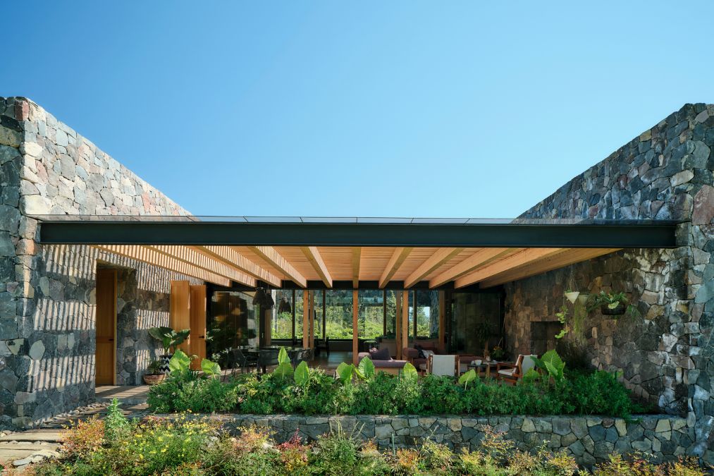 Featuring a stone wall and a covered patio, the FS House offers a unique and inviting living space.