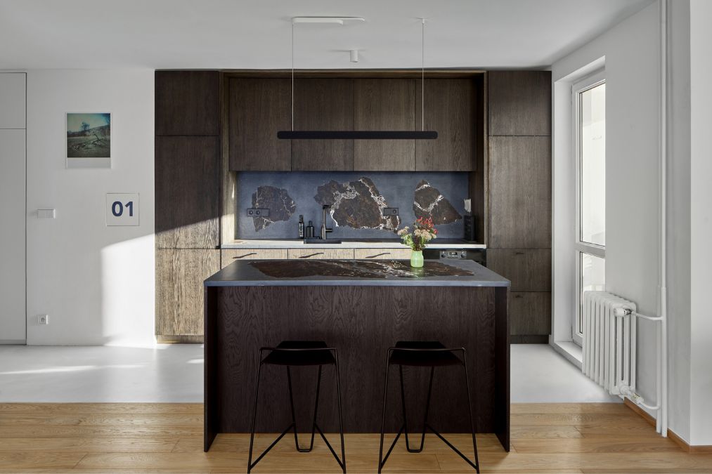 This is a detailed shot of the kitchen section, highlighting the elegant style achieved through the use of dark wood-colored cabinets and a center island. 