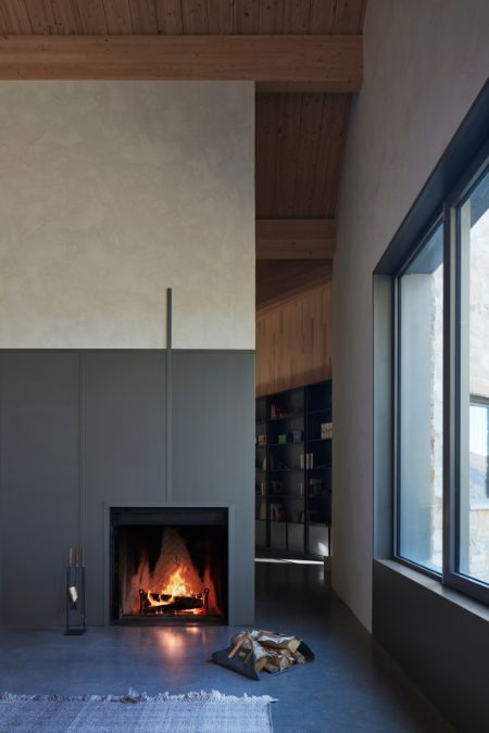 An indoor fireplace is positioned in close proximity to a sizable glass window.