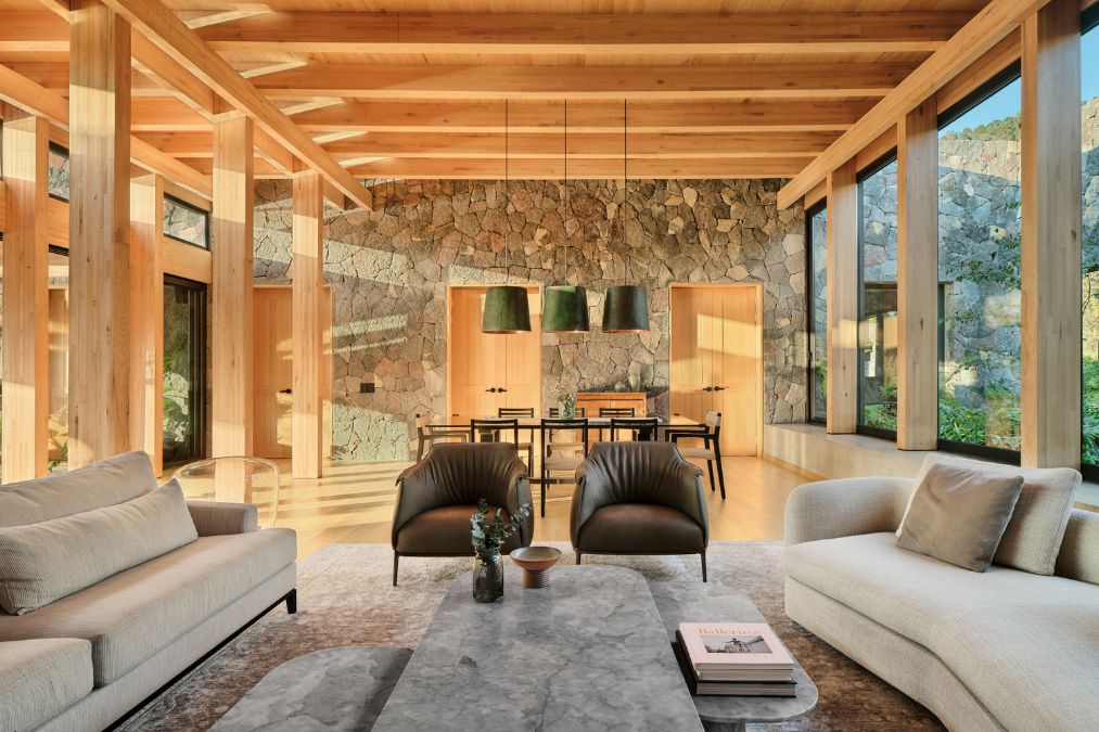 A fully-furnished living room boasts a stone wall as one of its prominent features.