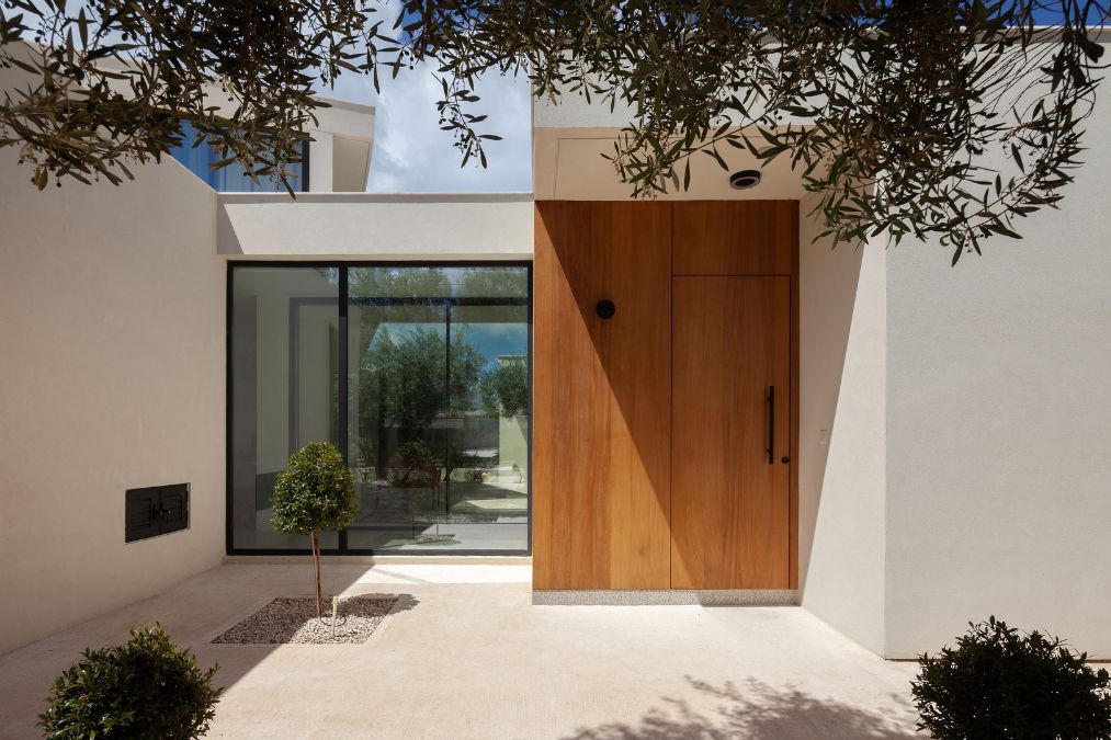 This is an exterior photograph showcasing the main entrance of the residence, featuring a substantial wooden door and glass windows.