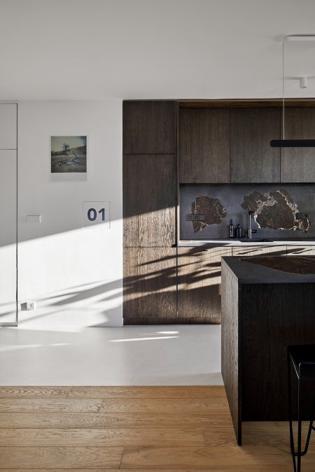 This is a partial view of the kitchen section where the wooden plank floors end, and the flooring transitions to a pure white color, extending to the edge of the space. 