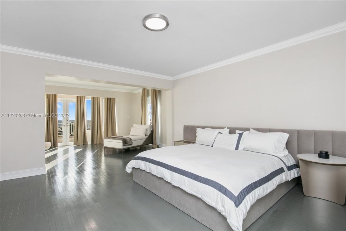 The master bedroom features a queen-size bed, and the wooden flooring gives off a cozy feel to the room.