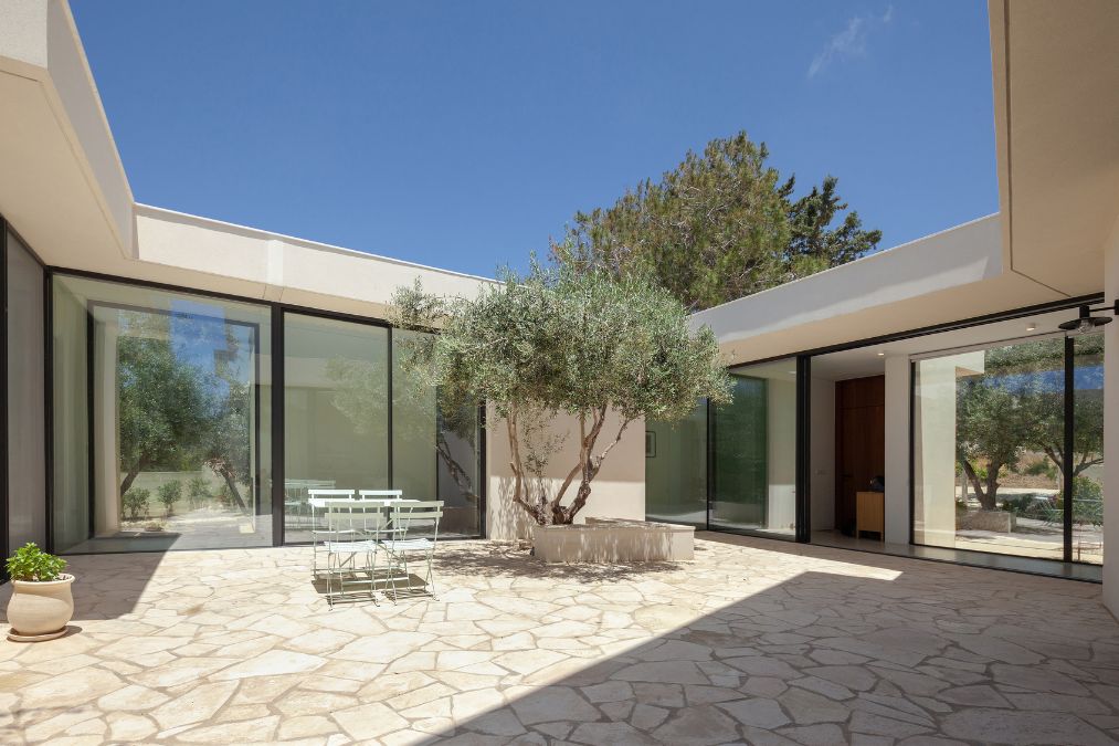 This is a daytime exterior photograph portraying a commodious patio with a small dining set positioned within its premises.