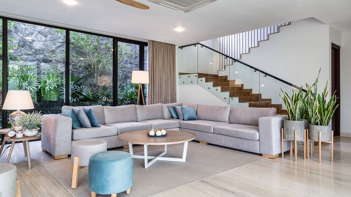 The photograph captures a unique perspective of the interior design of the living area, showcasing its expansive glass walls and the elegant staircase that serves as a centerpiece of the space.