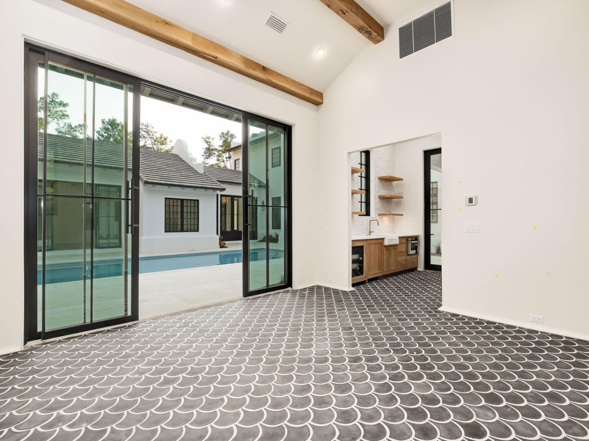 The room features an exposed wooden beam and glass doors leading to the swimming pool