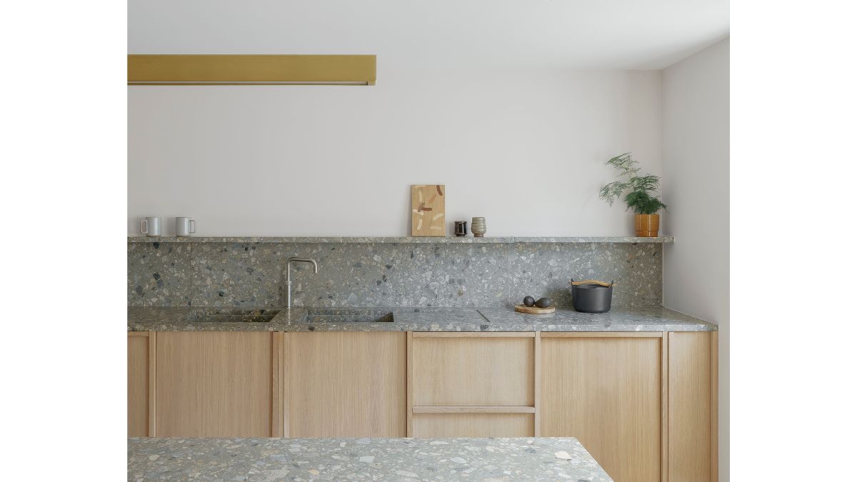 The kitchen contains concrete wall, stone sink, and a wooden cabinetry, over-all it suits.