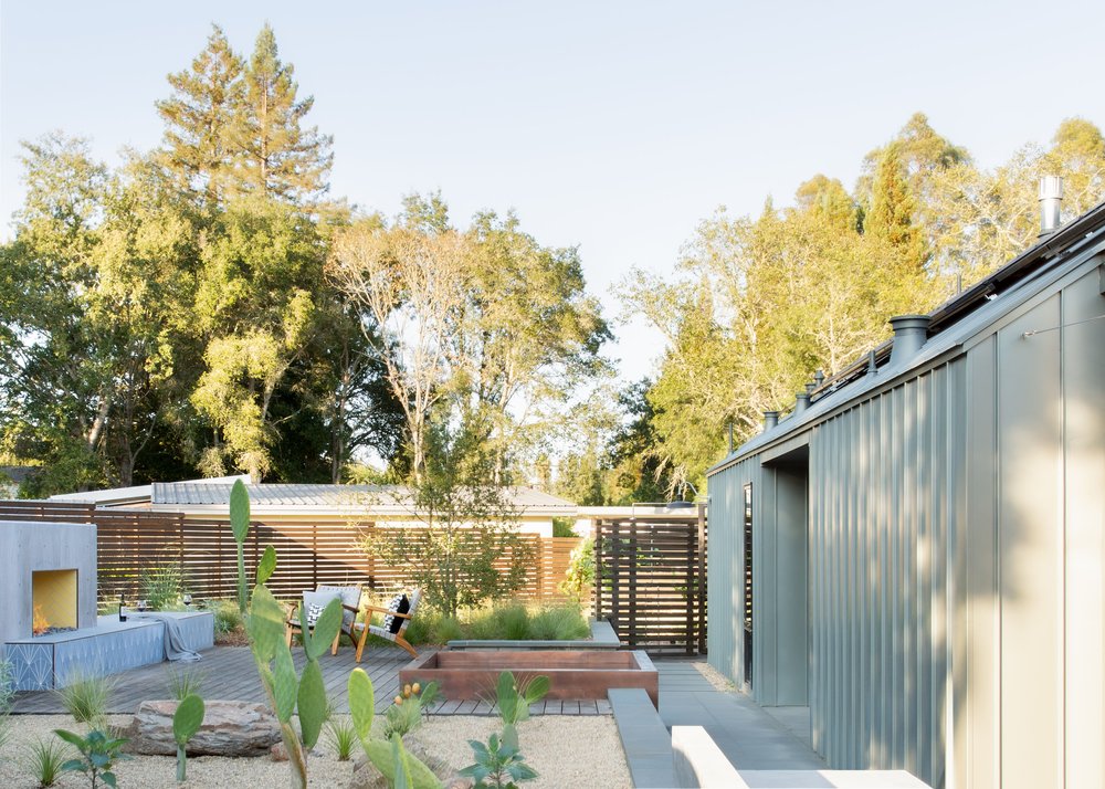 The Main House and a Guest House with Bike Barn joined in the middle by a central outdoor gathering space anchored by a fireplace.