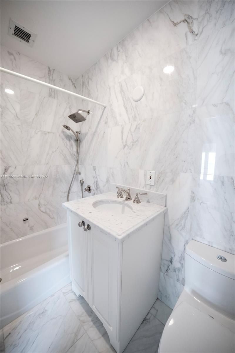 The bathroom features a built-in bathtub with a shower curtain for privacy and a free-standing vanity.