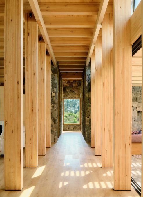 A lengthy wooden hallway is adorned with a stone wall.