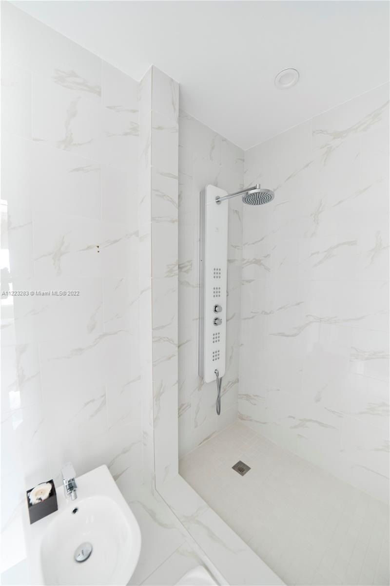 The bathroom features a shower cubicle with a tile wall.