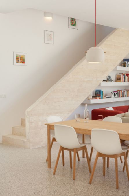 This is an interior photograph featuring the staircase of the residence, with a partial view of the dining set visible in the background.