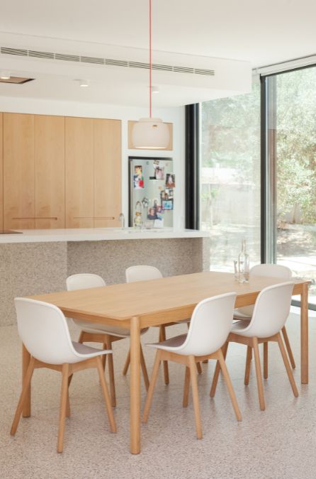 This is an interior photograph showcasing the minimalist interior design of the dining and kitchen areas of the house.