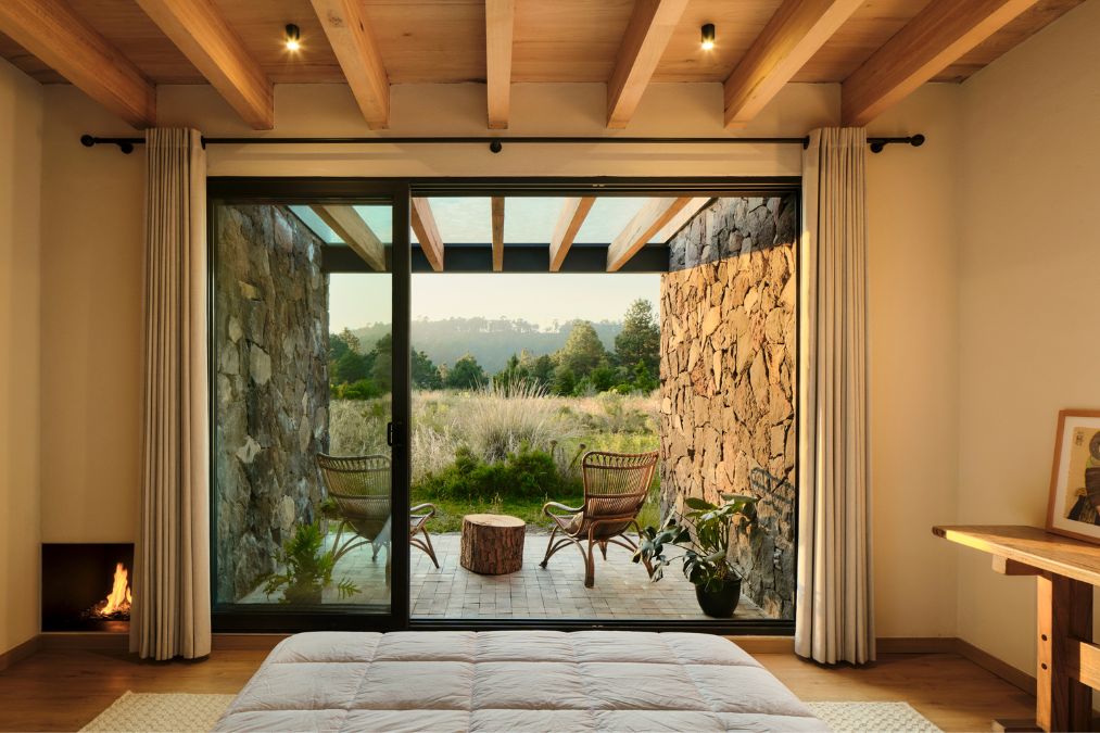 The bedroom is characterized by a stone wall and features sliding glass doors.