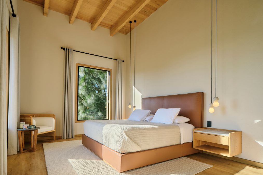 The bedroom includes a bed and a window, and features a minimalist design with a high ceiling.