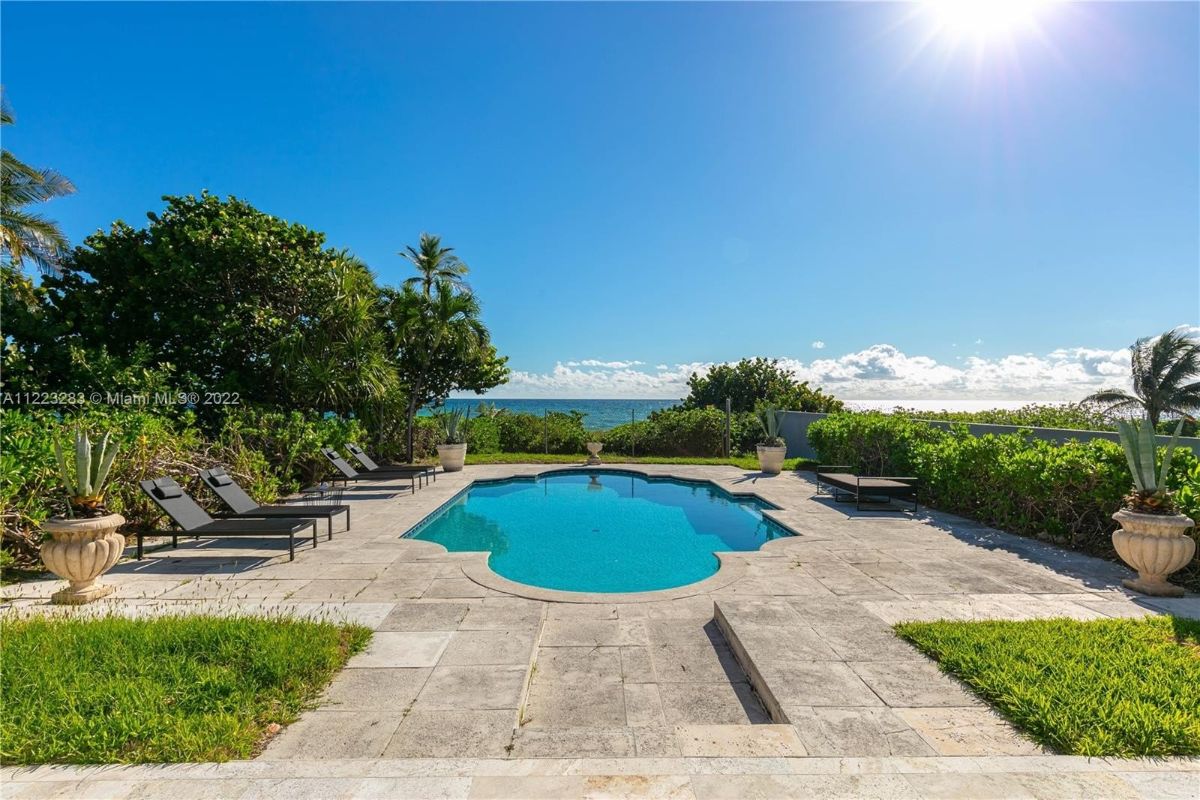 The backyard features a swimming pool and sun loungers, perfect for relaxation as it overlooks the ocean.