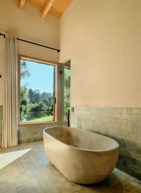 There is a large bathtub situated in the bathroom adjacent to a window.