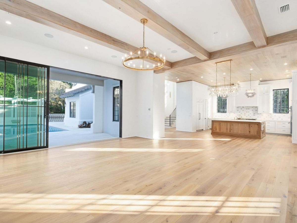 The house features wooden beams and wooden flooring that gives off a rustic feel and large glass doors that serves as ventilation.