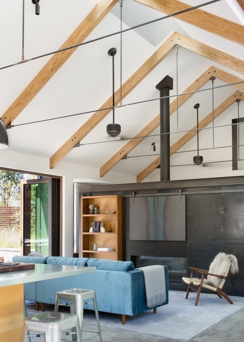 The living room that features cathedral-beamed ceiling, double-sided fireplace that served as the partition from the master bedroom.