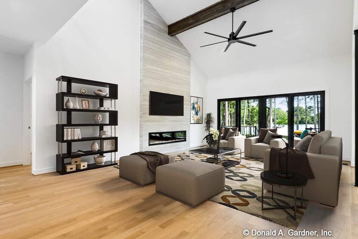 Great room with taupe seats, an electric fireplace with a TV on top, and a vaulted ceiling accentuated with a rustic wood beam.