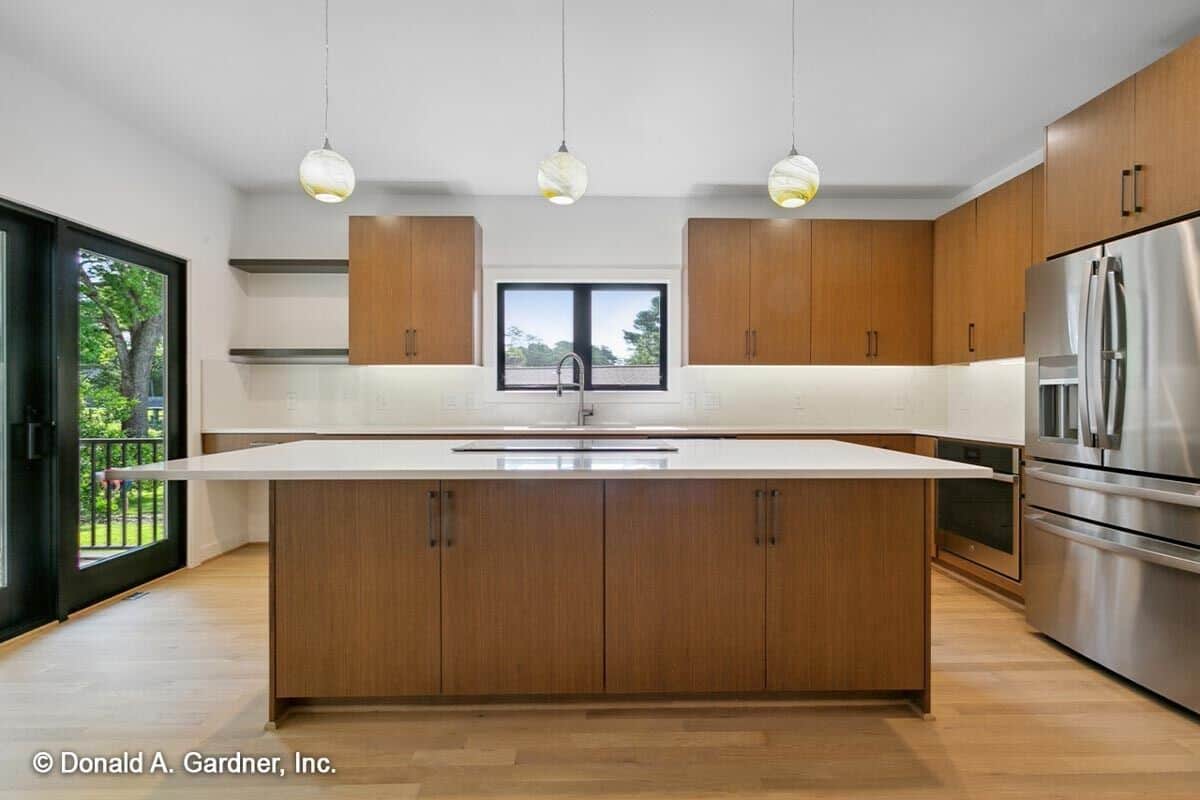 The kitchen is equipped with stainless steel appliances, wooden cabinets, and a large island fitted with a built-in cooktop.