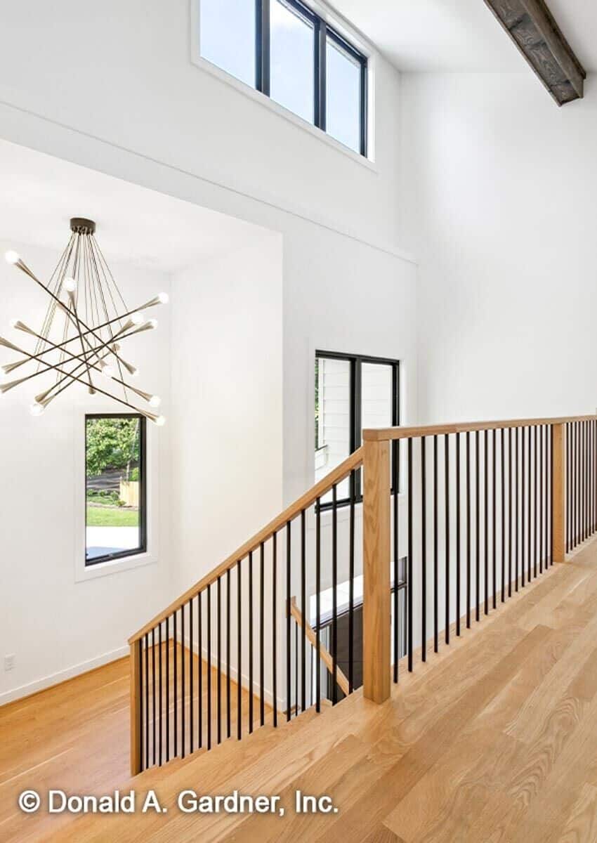 The second-level balcony has warm hardwood flooring and wrought iron railings overlooking the foyer below.