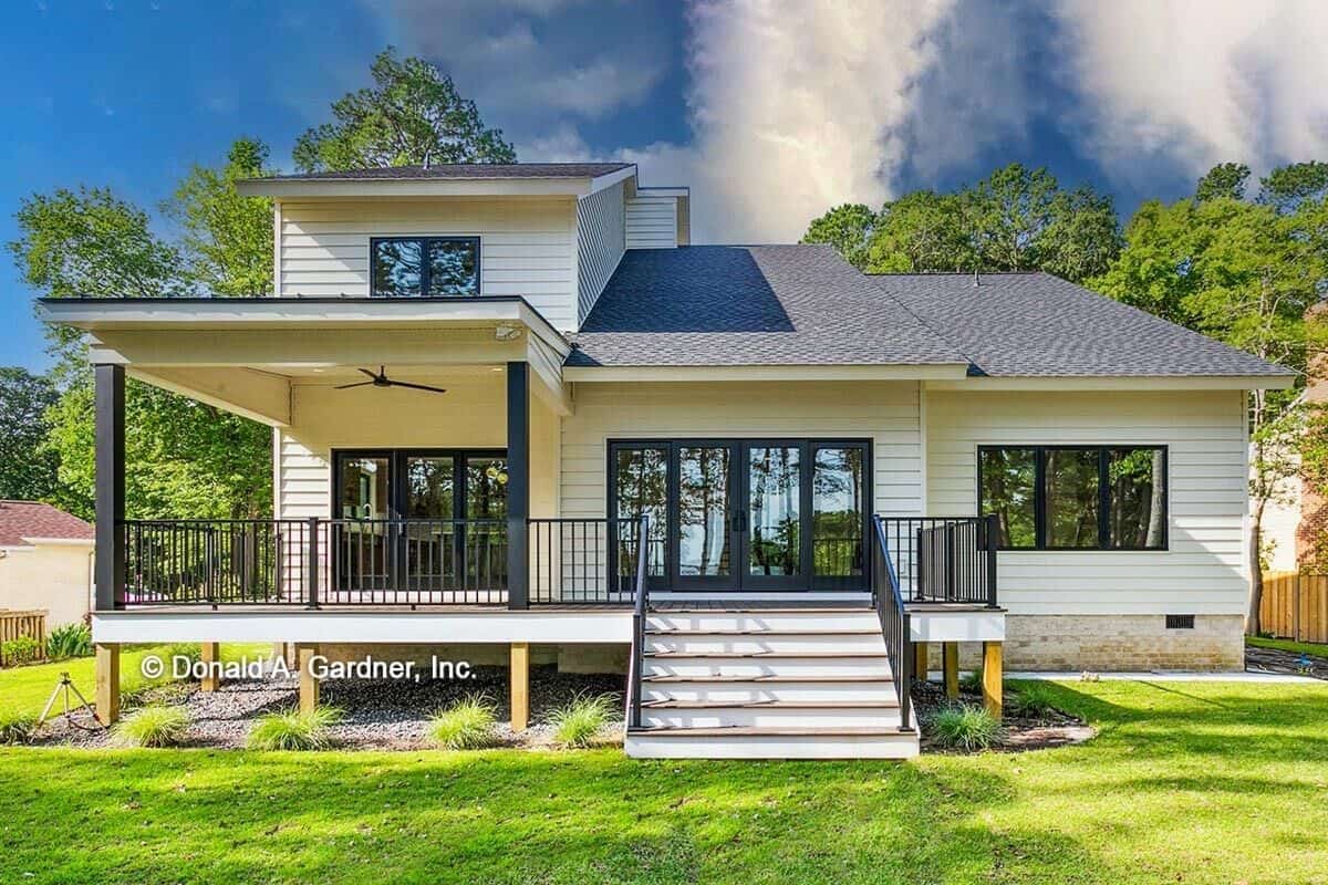 View of the house from the backyard showcasing its partially covered deck bordered by wrought iron railings.