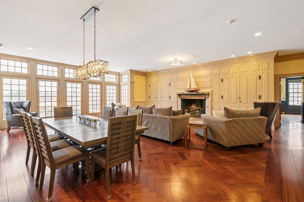 The formal dining area features a polished wooden table lit by a chandelier giving off a luxurious feel.