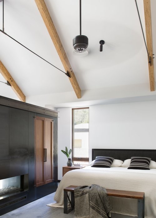 The primary bedroom is separated from the living space by a double sided fireplace within a custom wardrobe clad in steel and walnut.