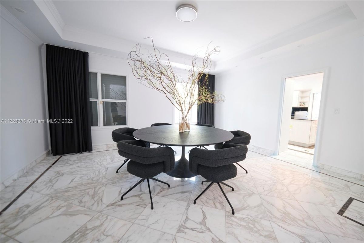 The dining room features tile flooring that blends well with the white paint and a round table for dining.