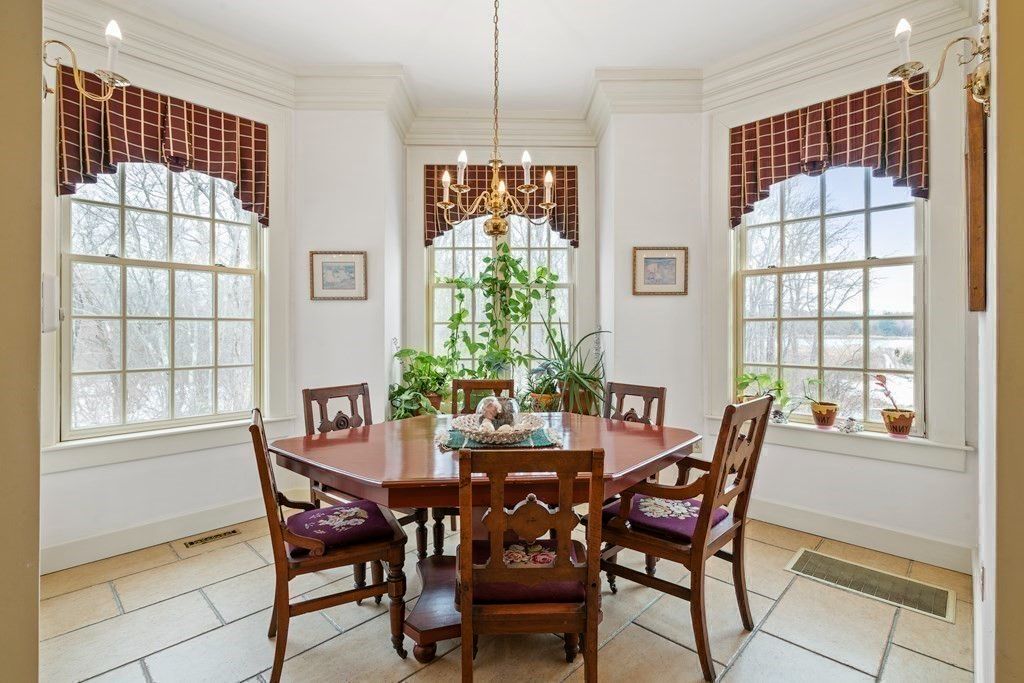 The dinette features a wooden table and glass windows that showcase the Merrimack river.