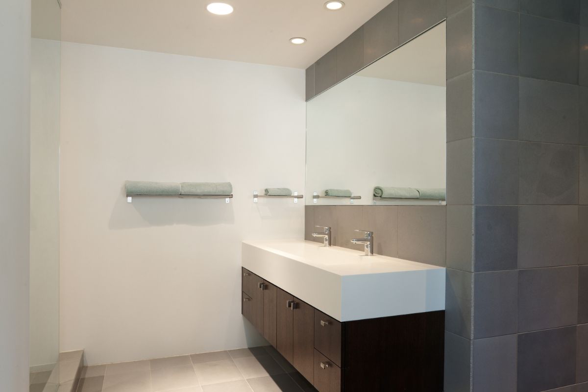 A bathroom with a counter-topped sink, a full-width vanity, and floating cabinets.