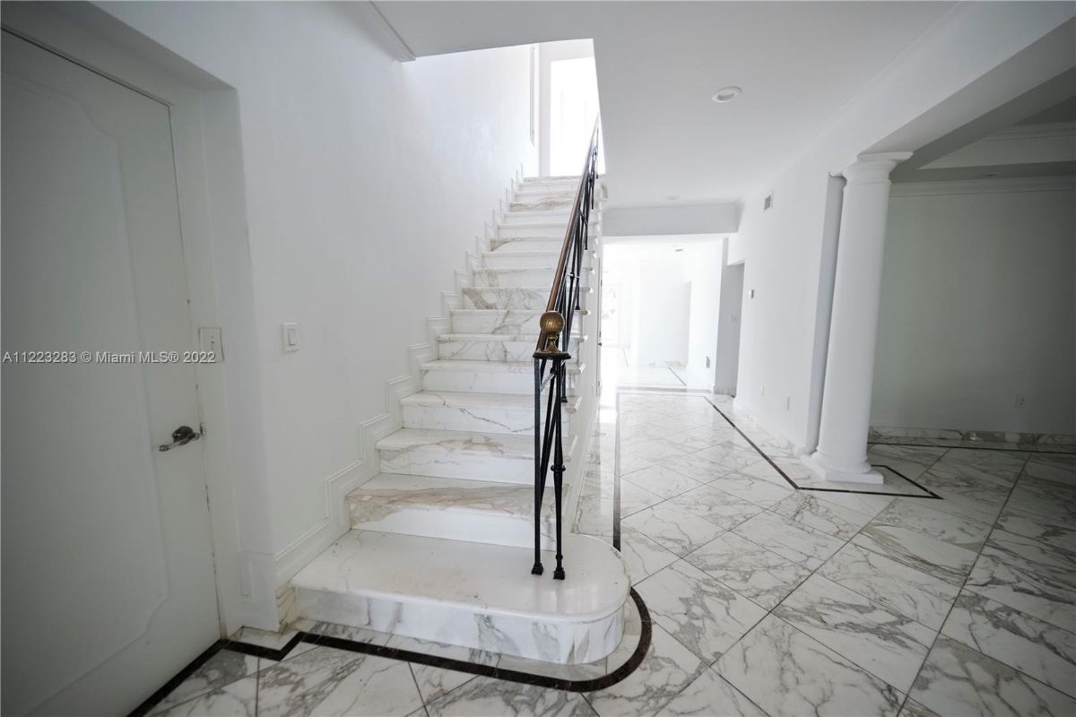 The staircase with tile steps and metal railing leads to the upper floors.