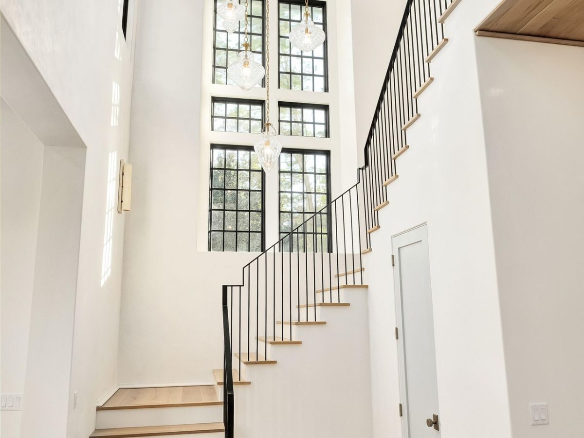 The house features a wooden staircase lit by luxurious chandeliers.