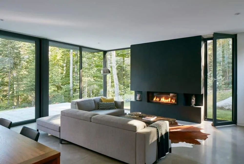 You can go the opposite direction of incorporating bright colors and instead go all in on gray like this room.  The light gray sofa is enhanced with the charcoal gray fireplace and wall.  In this instance, the dark wall, which admittedly is more stunning with surrounding floor-to-ceiling windows, pops out very nicely.  You'll notice there's also a yellow pillow on the sofa but that's not what really makes this room work... it's the dramatic charcoal gray fireplace.