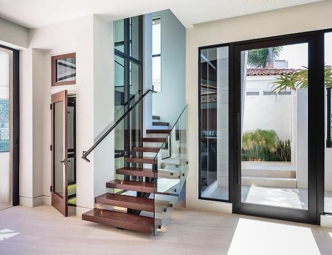 The home's interior features glazed doors and a modern staircase.