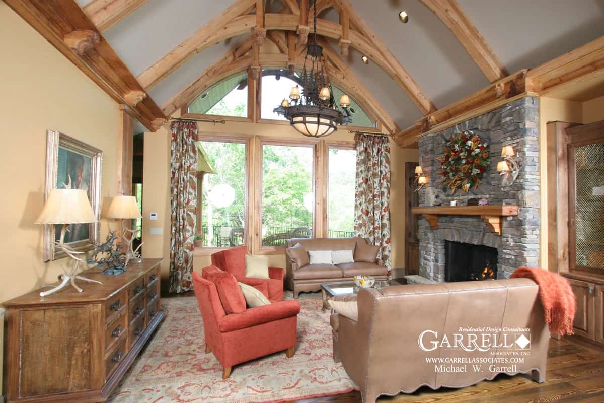 The lodge room features leather sofas, velvet armchairs, a stone fireplace, and a cathedral ceiling highlighted by exposed trusses.