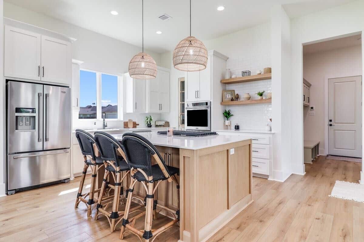 The kitchen is equipped with premium appliances, white cabinets, floating shelves, and a cooktop island.