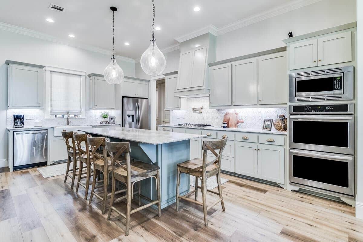 The kitchen is equipped with stainless steel appliances, white cabinets, a farmhouse sink, and a breakfast bar.