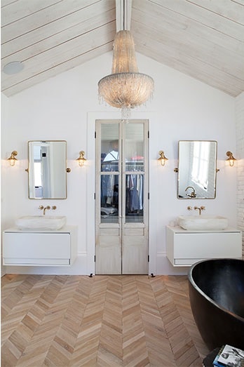 The primary bathroom is equipped with a black freestanding tub, his and her sink vanities, and a walk-in closet.