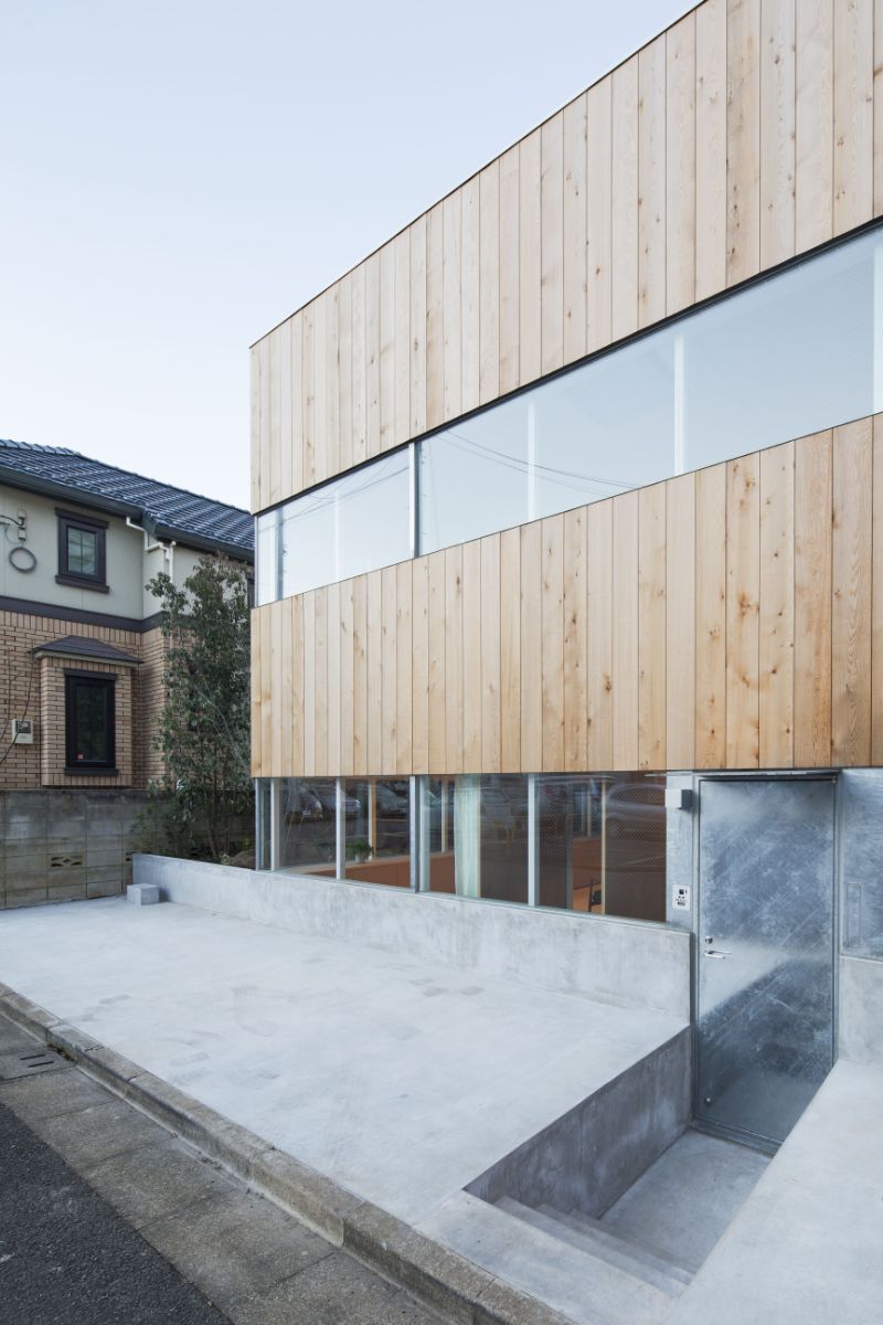 The house's street facade, with small steeps leading to the main entrance, the house has glass slits around the entire ground floor.